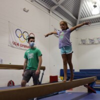 We still have spots open for Weeks 3 through 9. Girl and masked instructor on the balance beam