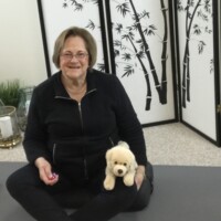 Image of yoga instructor for virtual class, on mat with dog